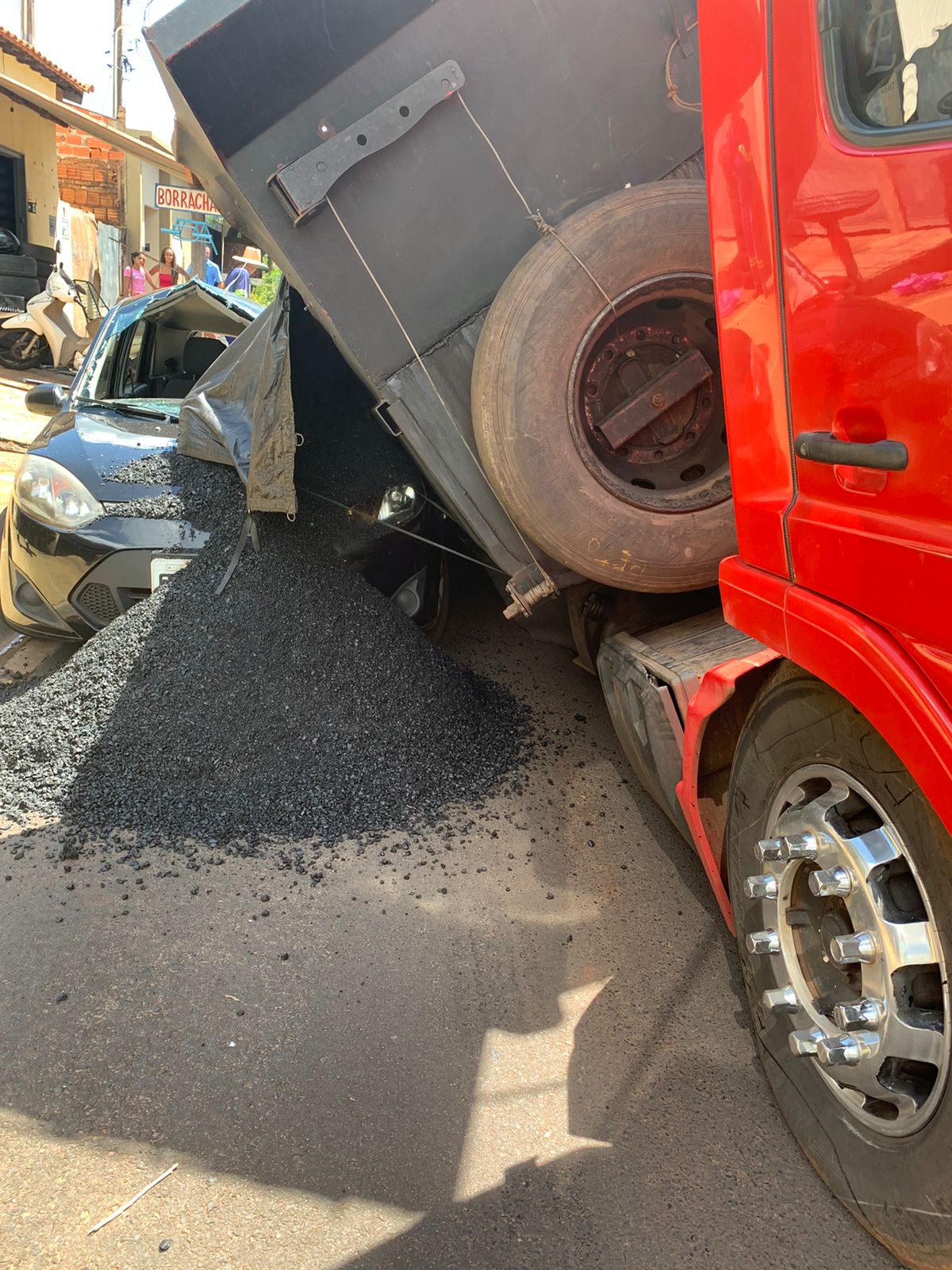 Caminhão carregado tomba sobre veículo no bairro América